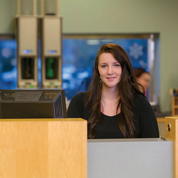 Female bank employee behind the counter waiting to assist the next customer