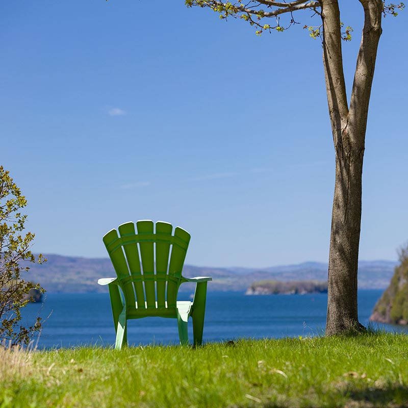 An Empty adirondack chair overlooking Champlain Lake