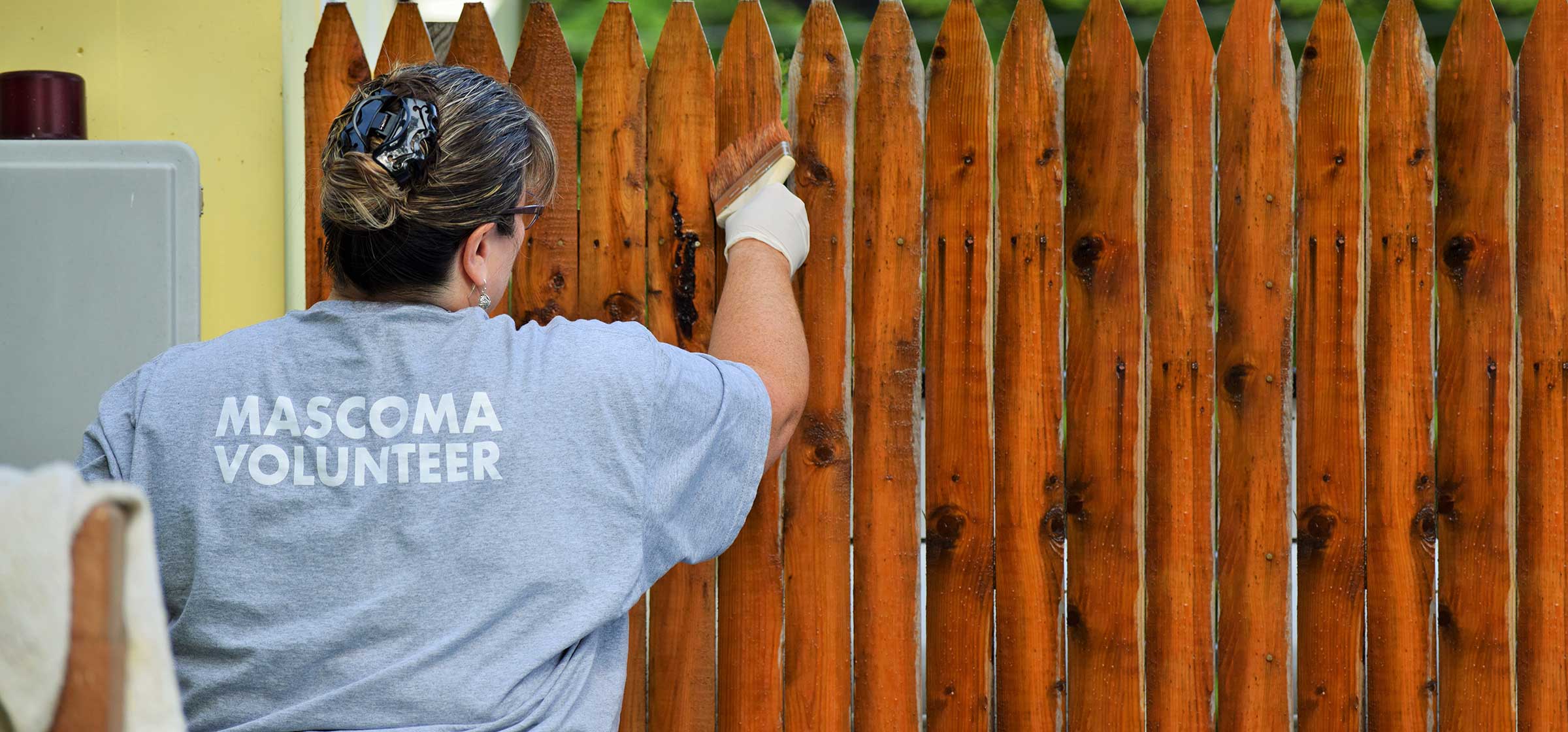 Mascoma bank employee staining a fence