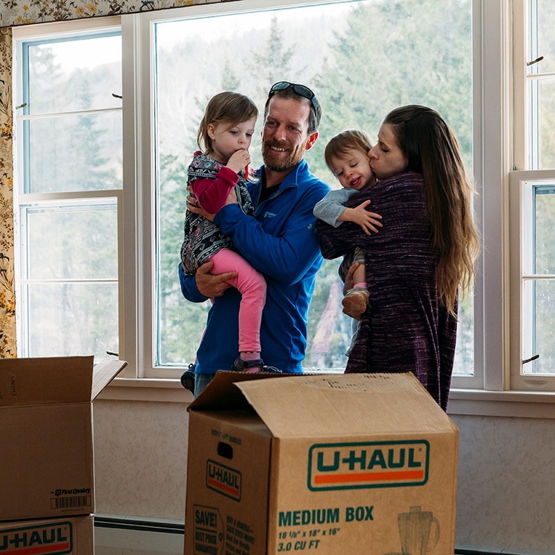 Family standing in front of window with U-Haul moving boxes in front of them