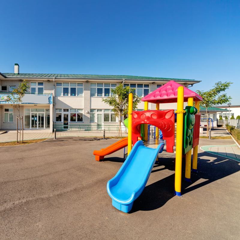 Colorful playground in front of a building with a bright blue cloud free sky