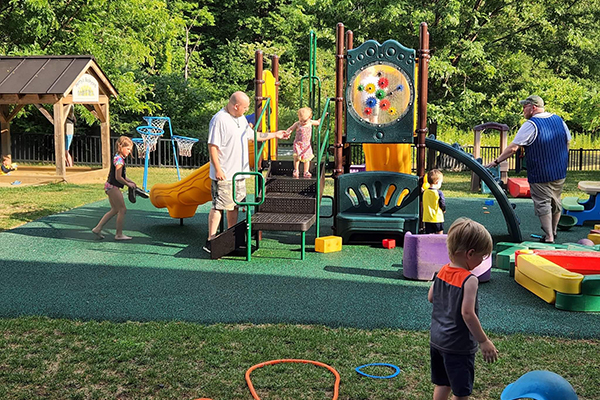 Outside playground with a few children and adults playing