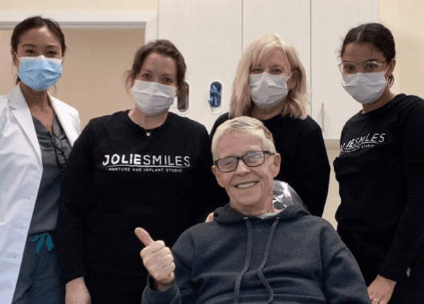 masked dentists around patient in wheelchair
