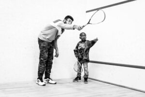 Portland Community Squash man teaching boy squash